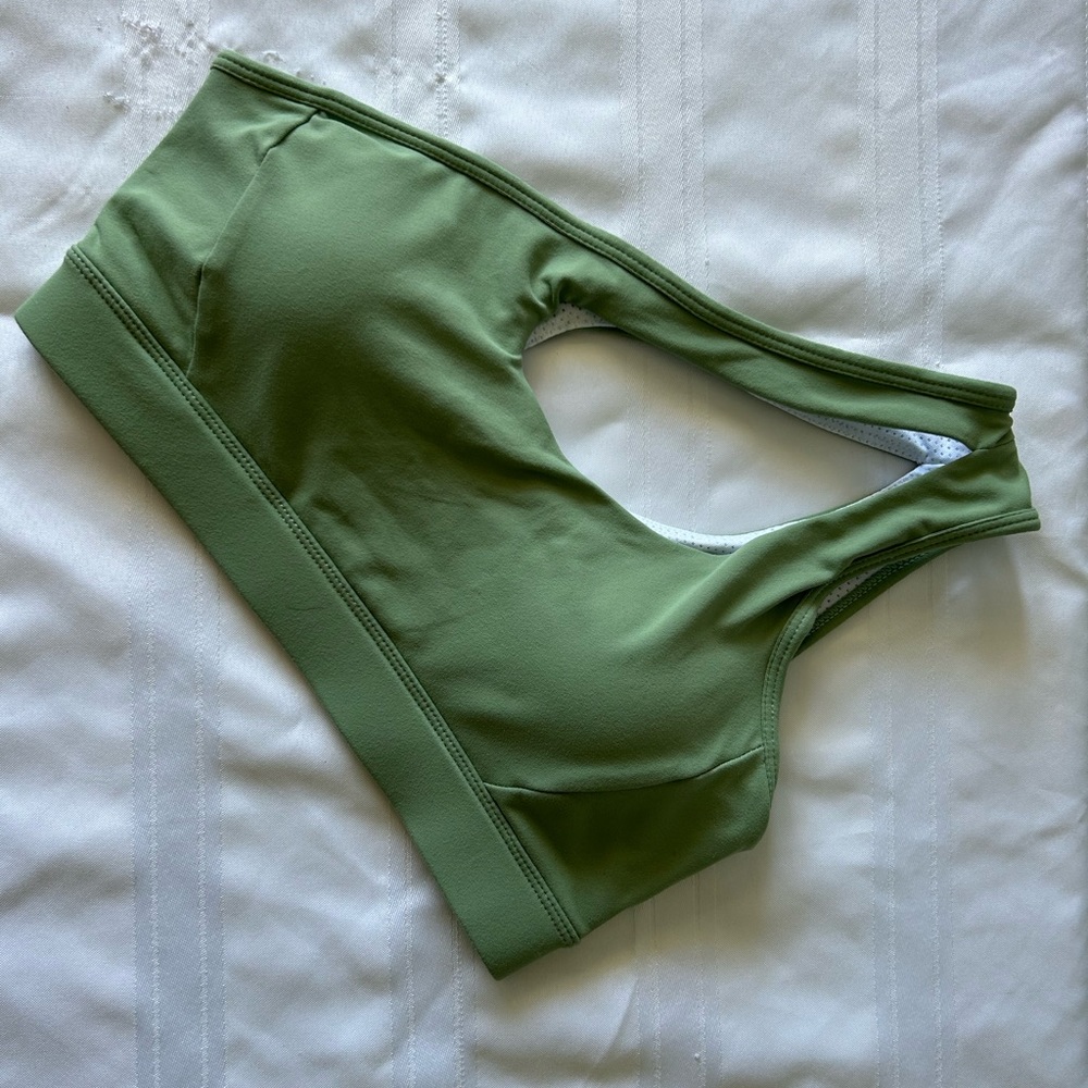 Two green single shoulder sports bras and one red sports bra with low cross back